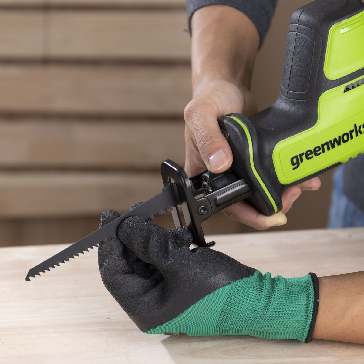 Person using a Greenworks power tool on a wooden surface